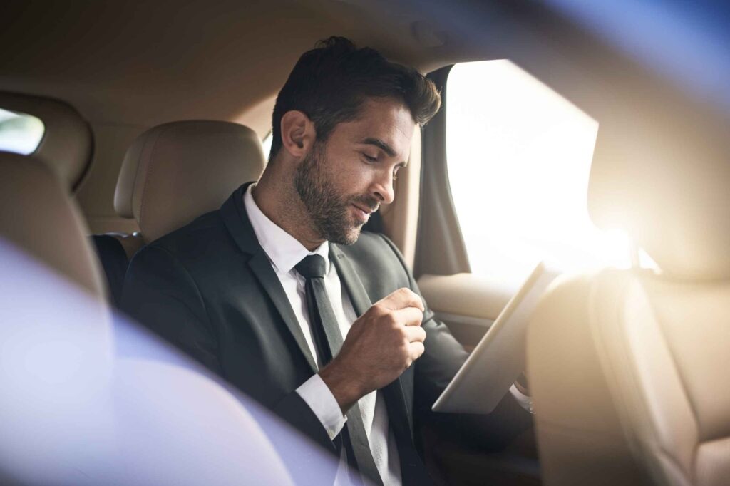 Business traveller working on a tablet in the back of a taxi