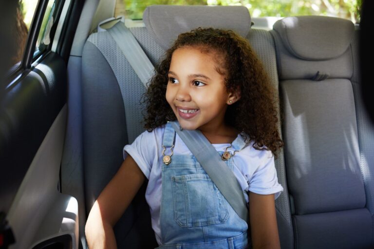Child wearing a seat belt in the back seat of a car