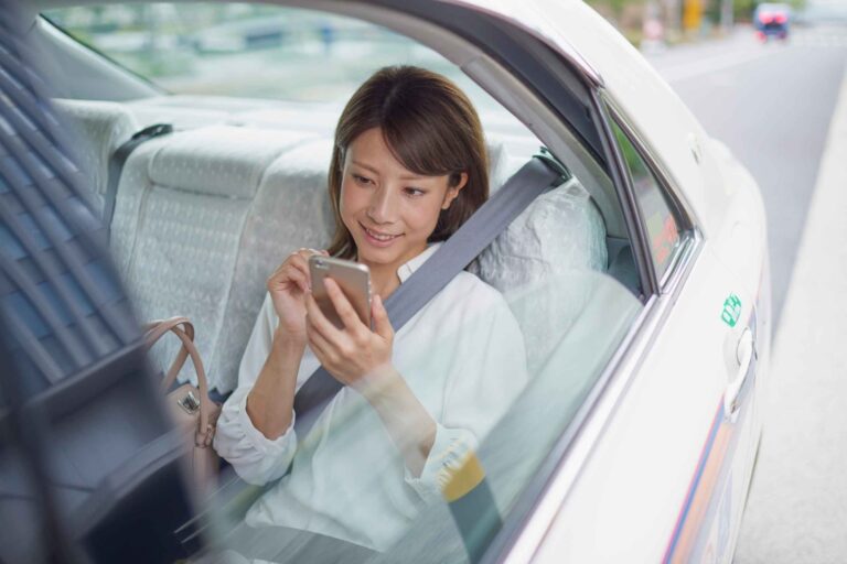 Passenger using her phone in the back seat of a white taxi