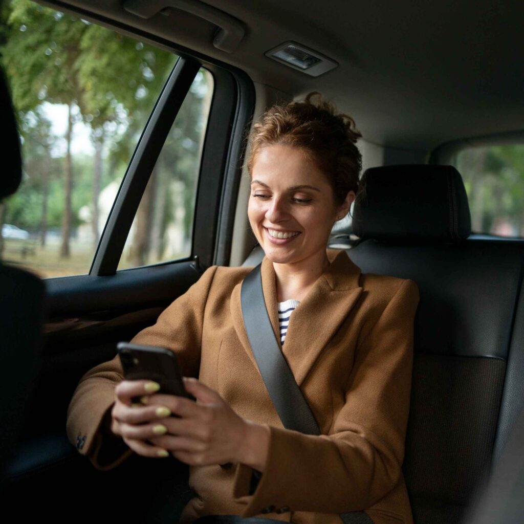 Passenger checking her phone in the back seat of a taxi