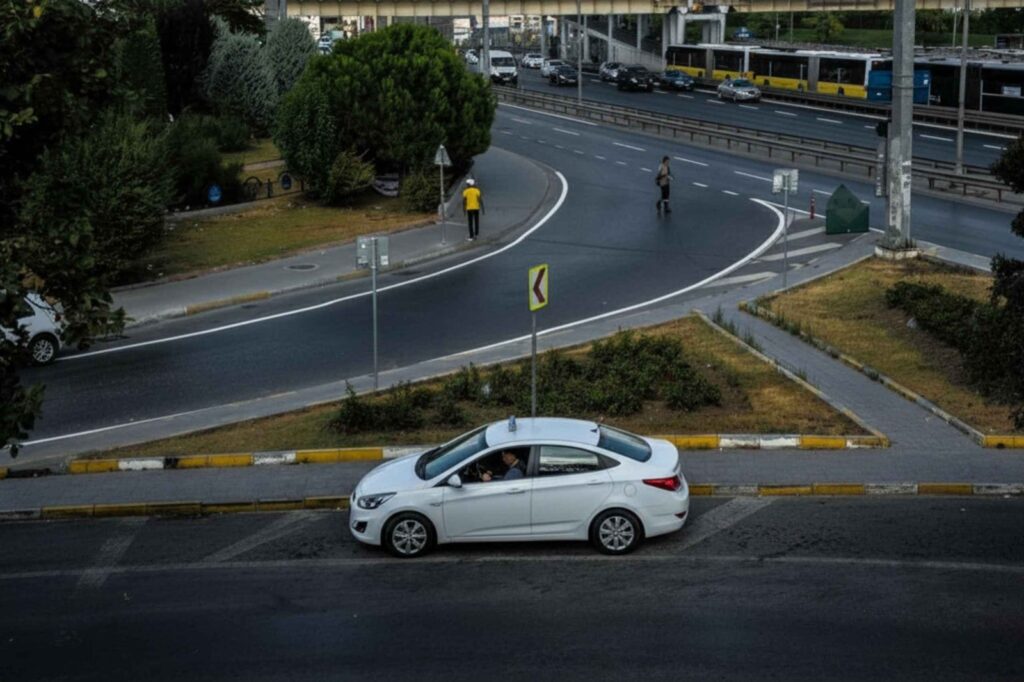 White taxi driving through a city intersection