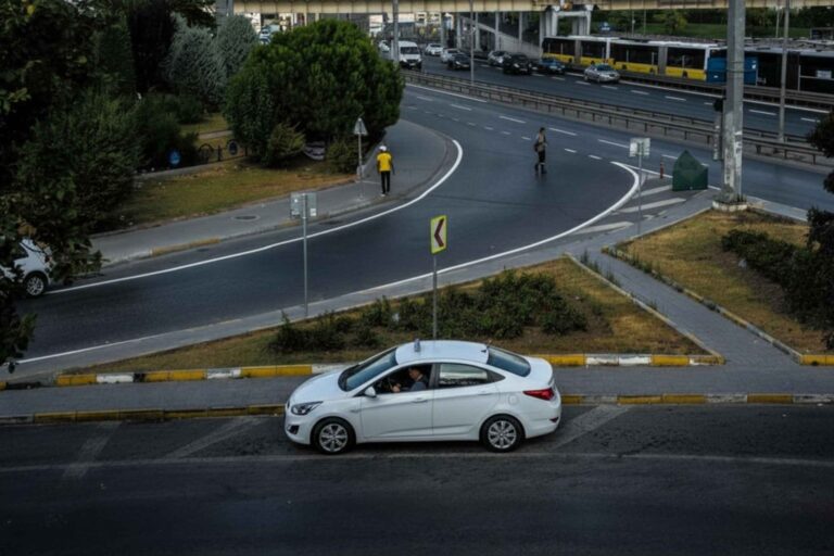 White taxi driving through a city intersection