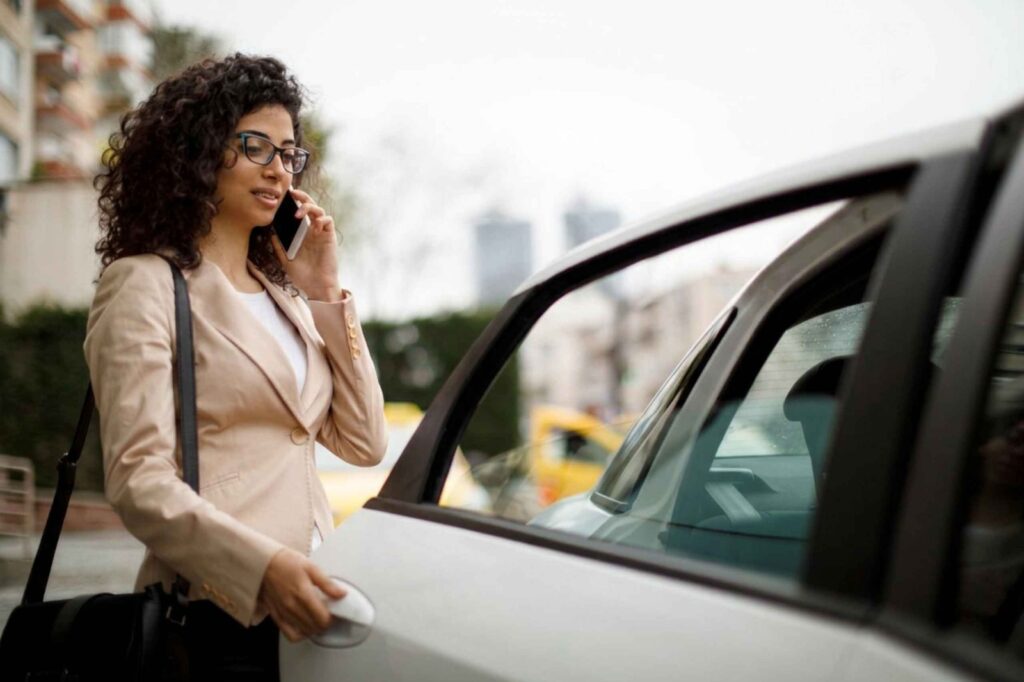 Woman on the phone opening the door of her taxi