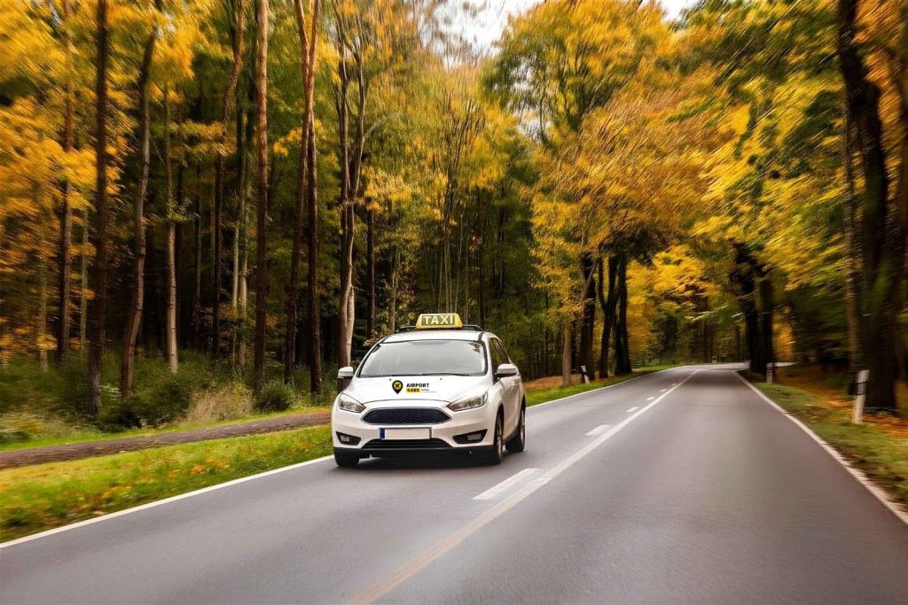 AirportCabs taxi driving on a tree-lined road near Spruce Grove
